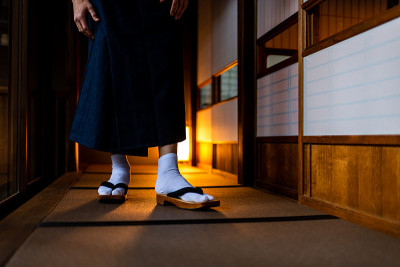 日本旅馆传统的房子房间低角度观看与男人在和服的腿特写脚与tabi白色袜子和得到鞋走过shoji滑动纸