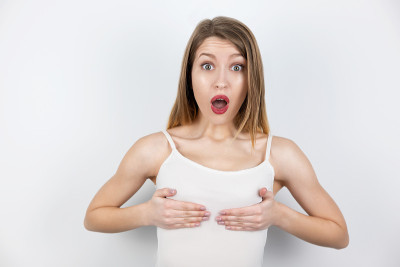 讽刺的是，年轻女子闭上她的乳房用手看着惊讶，身体正面的概念