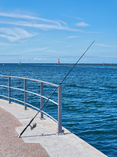波罗的海上的钓竿Warnemünde，以码头上的灯塔为背景。