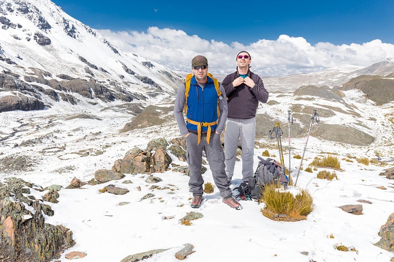 游客登山运动员站在雪山的顶峰。