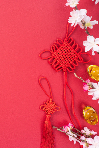 中国农历新年的设计理念-美丽的中国结与梅花孤立在红色的背景。