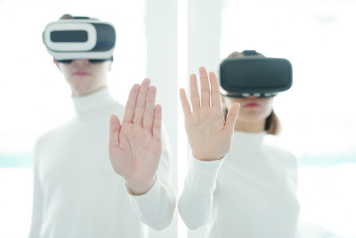 年轻的软件开发人员戴着vr头盔，双手放在摄像头前