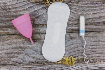 卫生巾，卫生棉条和月经杯以木制为背景。前视图。关键日子、月经、女性卫生的概念