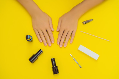 女人的手。俯视图美丽光滑的女人的手与专业指甲护理工具美甲在黄色的背景。健康女性指甲与黄色指甲油的特写