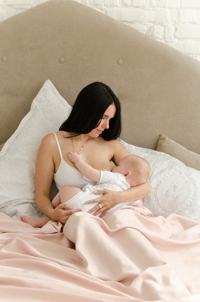 母乳喂养。年轻的母亲正在喂婴儿。家人在家里