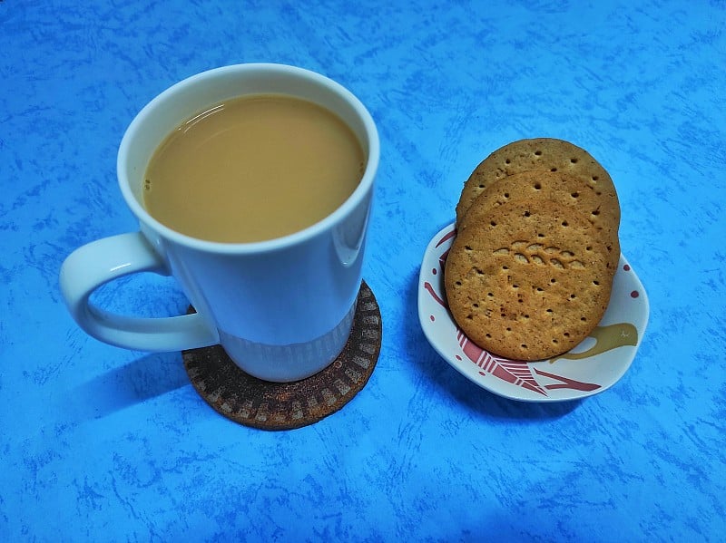 白杯子里的奶茶和三块饼干