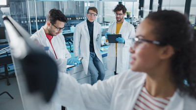 医学实验室:美丽的黑人女性科学家在董事会上写详细的项目数据分析，她多样化的同事团队倾听。解决问题的年