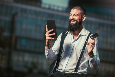 一名年轻的白人商人在户外手持平板电脑和信用卡
