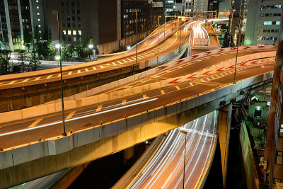 在日本东京，繁忙的西新宿高速公路十字路口的全景与灯光小径在夜间