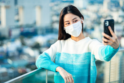 在曼谷的屋顶上用手机微笑的漂亮年轻女人的肖像。女性用手机做视频博客，生活在社交媒体中。