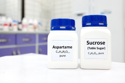 选择性集中一瓶纯阿斯巴甜人工甜味剂和蔗糖或蔗糖化学化合物的比较。白色的实验室背景和复制空间。