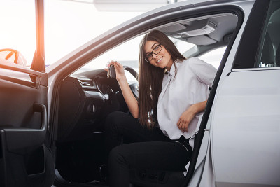 年轻快乐的女人拿着钥匙靠近车