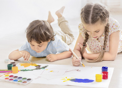 小孩子们躺在地板上用颜料画画