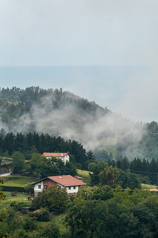 一个雾气弥漫的山顶上的小镇。在Lekeitio旁边的ispaste的春天，Bizkaia的风景。巴斯