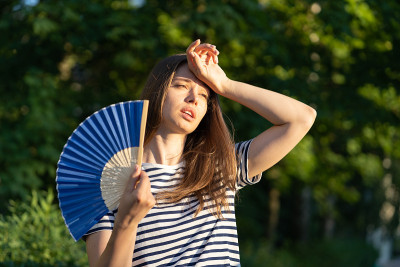 年轻女子在户外中暑。不开心的女孩觉得不好的温度摸额头