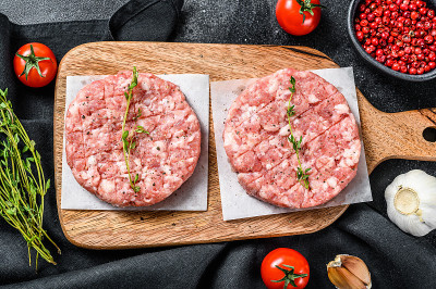 生猪肉片，碎肉饼放在砧板上。有机肉。黑色背景。俯视图
