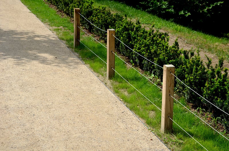 a low fence of land with three steel ropes and woo