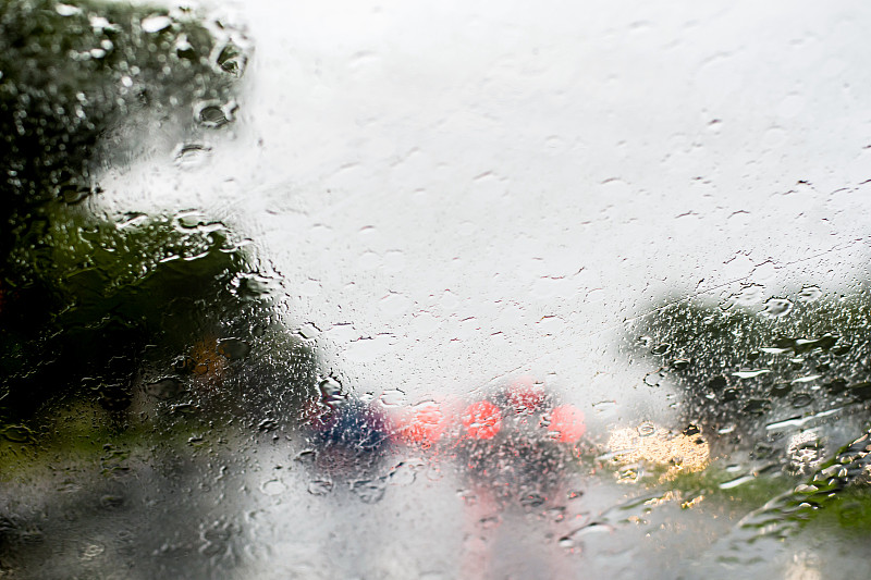 模糊的散焦图像大雨透过挡风玻璃。降雨、山洪背景