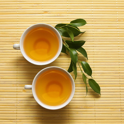 绿色的树枝和瓷杯茶在垫子上