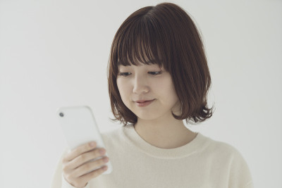 一名亚洲年轻女子在用智能手机