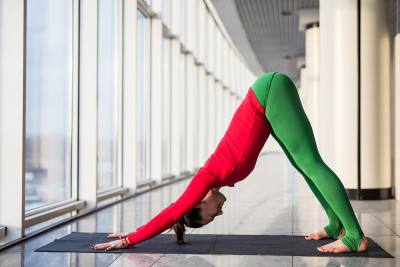 作为shirshasana。美丽的瑜伽女人在一个大窗户练习