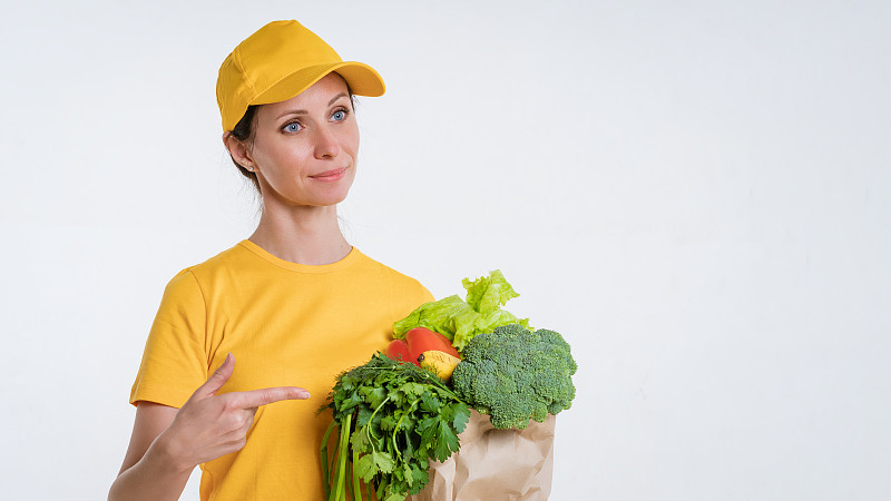 一个穿黄衣服的女人，在白色的背景下送一包食物