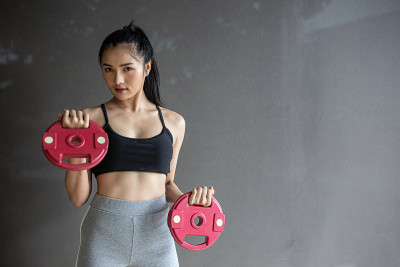女性用两个哑铃负重板锻炼