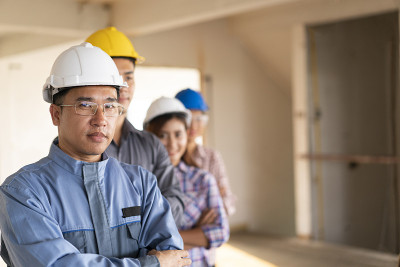 亚洲工程师的肖像被交叉双臂规划在建筑工地，工程团队的概念