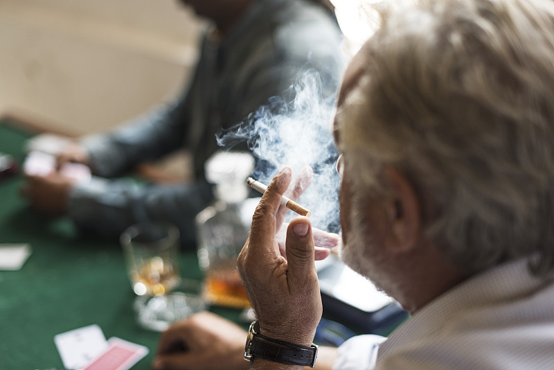男人一边打牌一边抽烟的侧视图