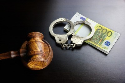 黑桌子上的法官木槌、手铐和欧元现金