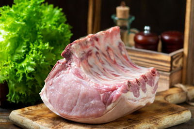 生猪腰肉放在一块木板上，放在棕色的木桌上。木背景上的生猪肉。乡村风格。空间的文本