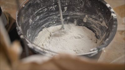 灰泥油漆工用这种混合物涂墙壁。工人摆弄桶里的灰浆