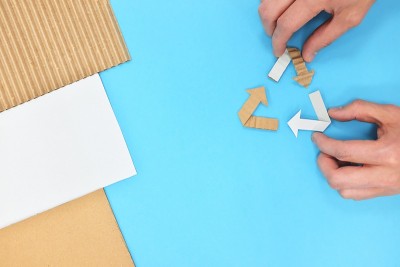 回收标志平躺在蓝色的背景与手。回收纸纸板。