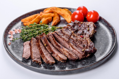 美味多汁的新鲜牛排与香料和香草在白色的背景