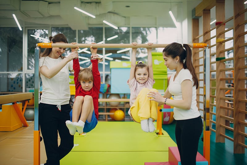 在幼儿园或小学体育馆做引体向上运动的孩子们。儿童运动健身理念。