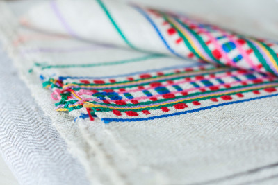 A stack of woven linen towels with embroidery, tra