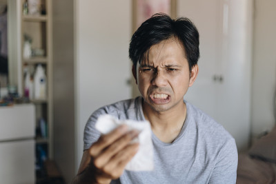 一名年轻亚洲男子震惊地看着手中的纸巾