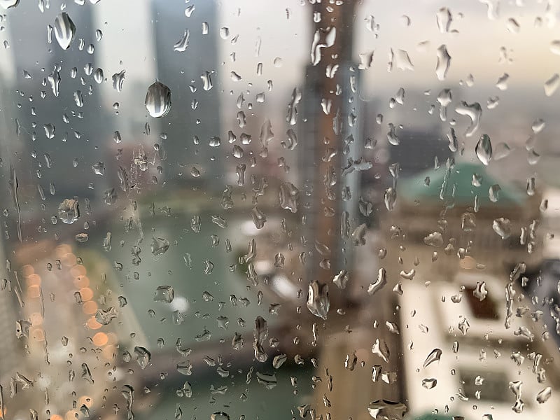 在夏季风暴期间，雨滴在窗户表面倒映出芝加哥河城市景观的图像