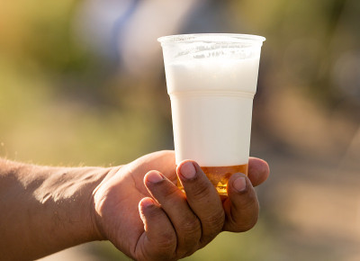 手里拿着一杯啤酒，里面有白色的泡沫