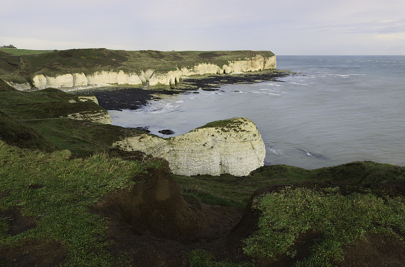 海面上的日出和海岸线上明亮的天空下被侵蚀的白垩峭壁。Flamborough,英国。