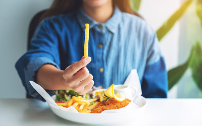 一个女人拿着一块炸薯条和炸鱼和薯条放在餐馆的桌子上