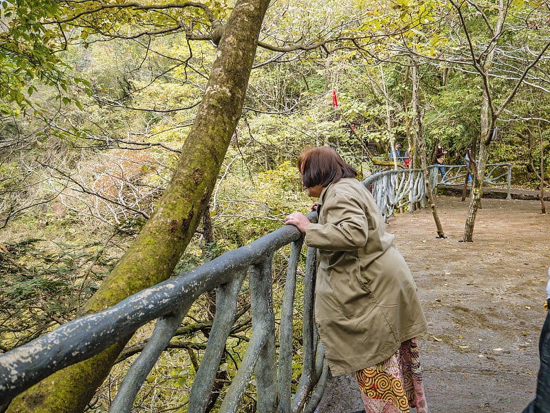 美丽的亚洲老年妇女在自然步道自然天门山和晴朗的天空在中国张家界城市。中国湖南张家界市的旅游目的地天门