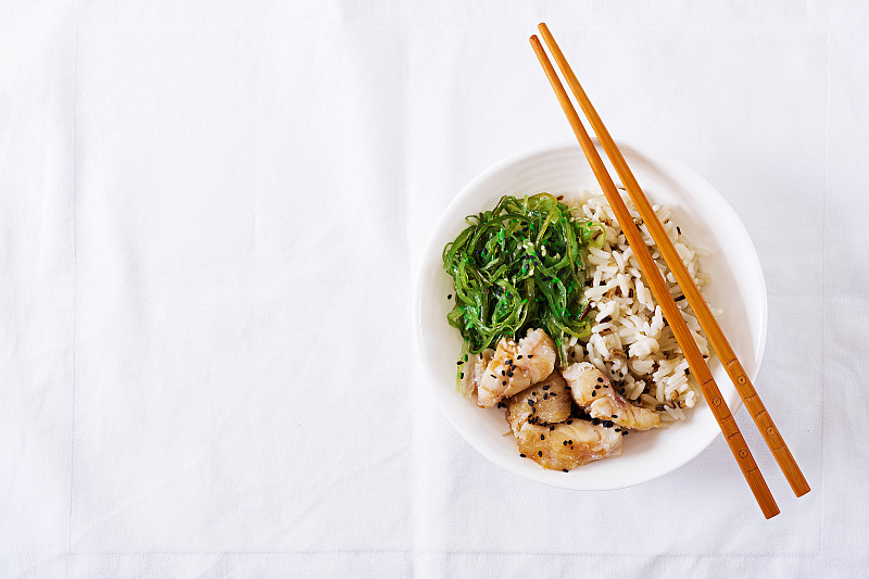 日本的食物。一碗米饭，白鱼和裙带菜或海带沙拉。前视图。平躺