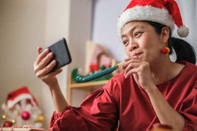 亚洲妇女戴圣诞帽视频电话聚会与朋友与移动电话桌上在家里