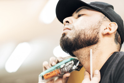 Close-up of a young man shaving his beard with a p