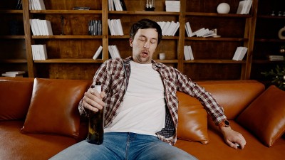 年轻时的酒瘾。白人男性无法停止喝酒，喝醉的孤独男性从瓶子里喝酒。圣诞节和新年期间的孤独、抑郁和酗酒