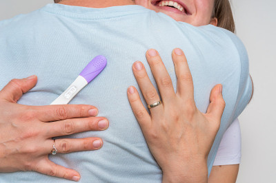 怀孕测试呈阳性的妇女拥抱她的丈夫