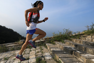 健身女子越野跑者在山顶的长城上奔跑