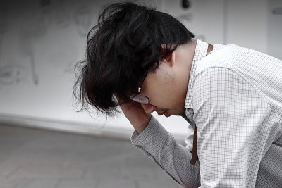 压力沮丧的年轻亚洲商人用手捂着脸。