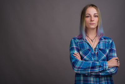 工作室拍摄的年轻美丽的女人与多色头发穿着蓝色格子衬衫对灰色的背景
